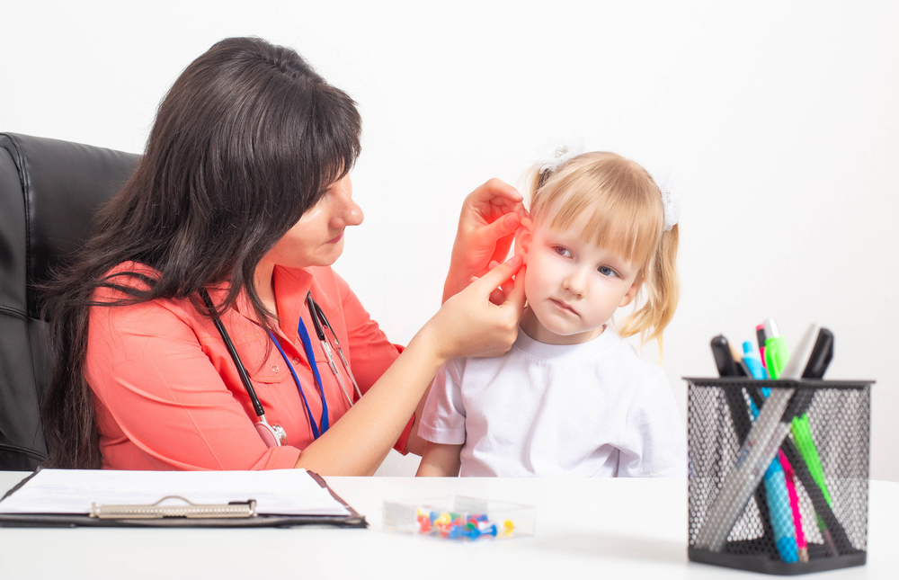 otolaryngologist examines the ear of a little girl who has pain in her ear.