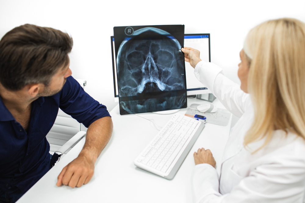 ent specialist reviewing xray of sinuses with patient.