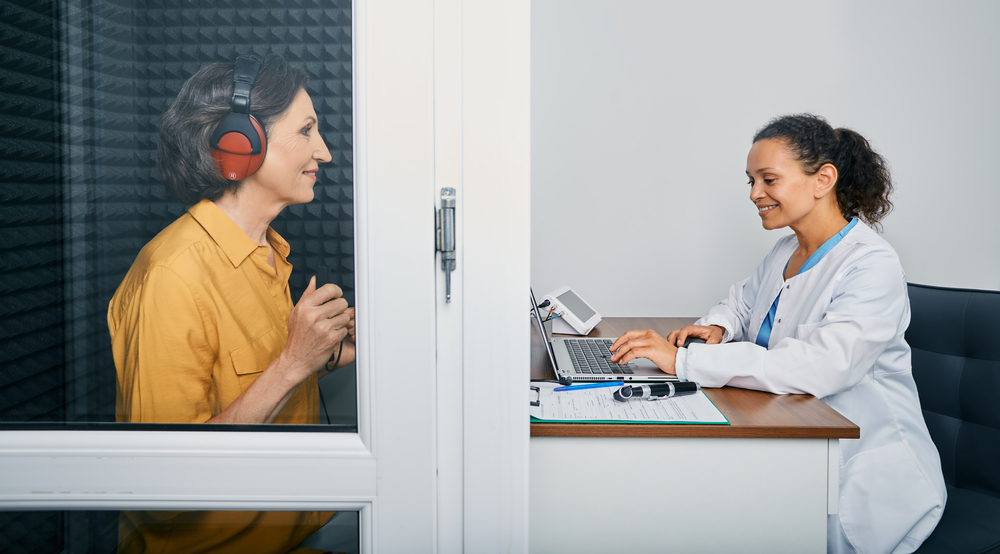 hearing specialist performs hearing test on patient.