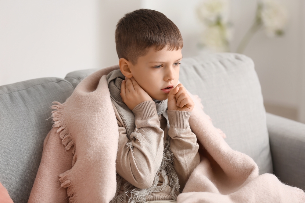 child with cough sitting with blanket.
