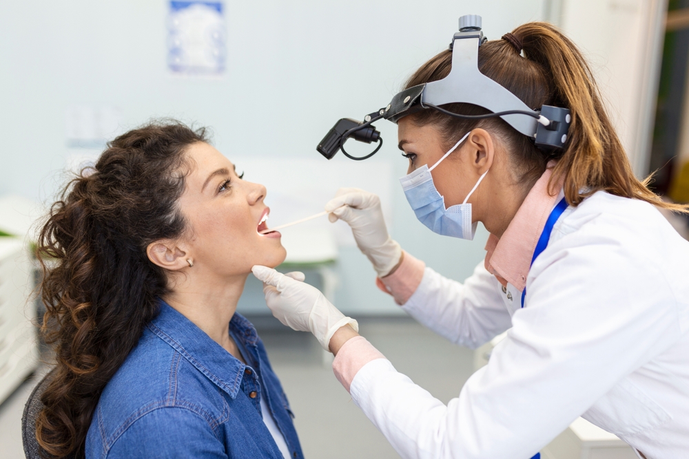doctor evaluating female patient's tonsils.