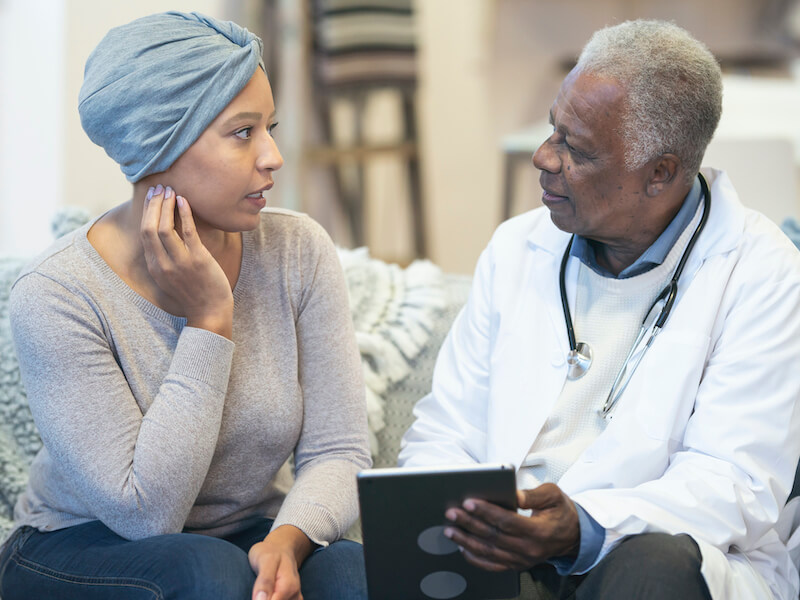 Adult woman suffering from hearing loss after having chemotherapy treatments discussing symptoms with her doctor.