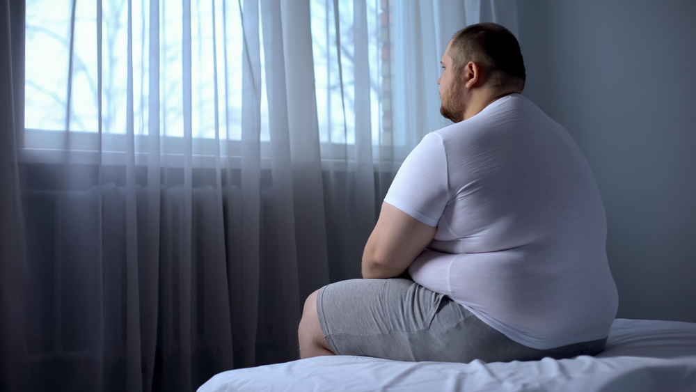 obese man sitting on the bed.