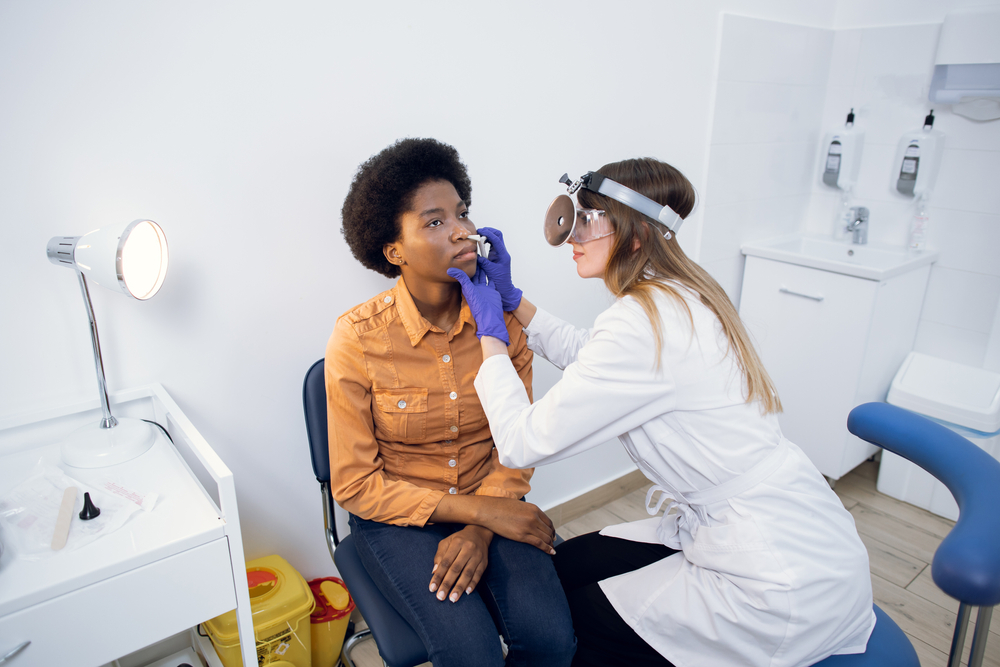 female ENT doctor examines nose of patient.
