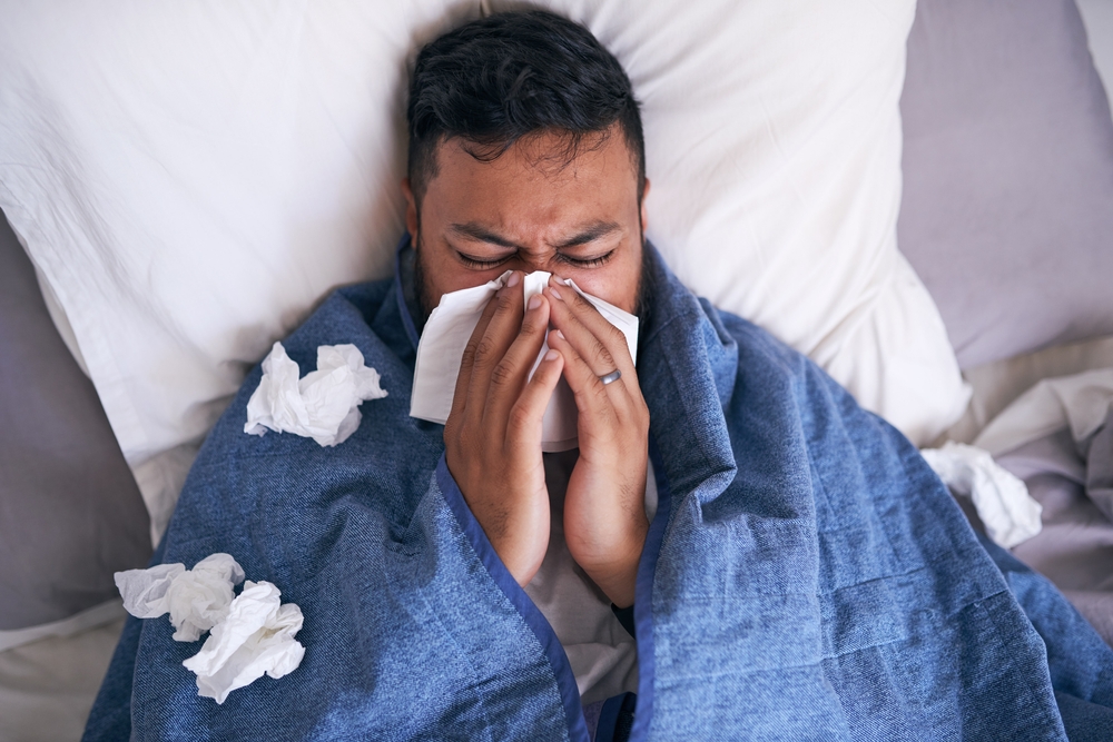 man suffering from sinus infection in bed.