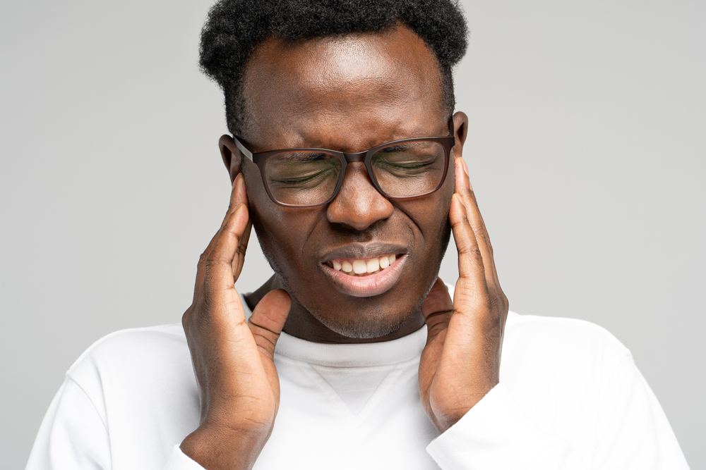 African American millennial man suffering from tinnitus.