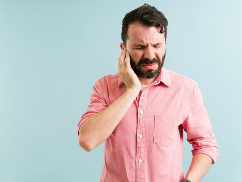 Worried man listening to a ringing in his ear. Tinnitus concept