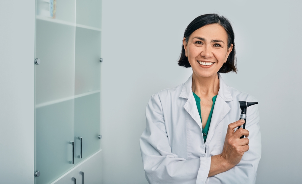 Female ENT physician smiling in a white coat.