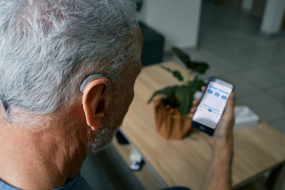 Man with hearing aid in ear using his cellphone.
