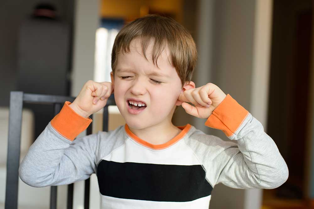 Young boy pressing his fingers to his ears, a common sign of ear discomfort, from Intracoastal Hearing Center in Vero Beach, FL